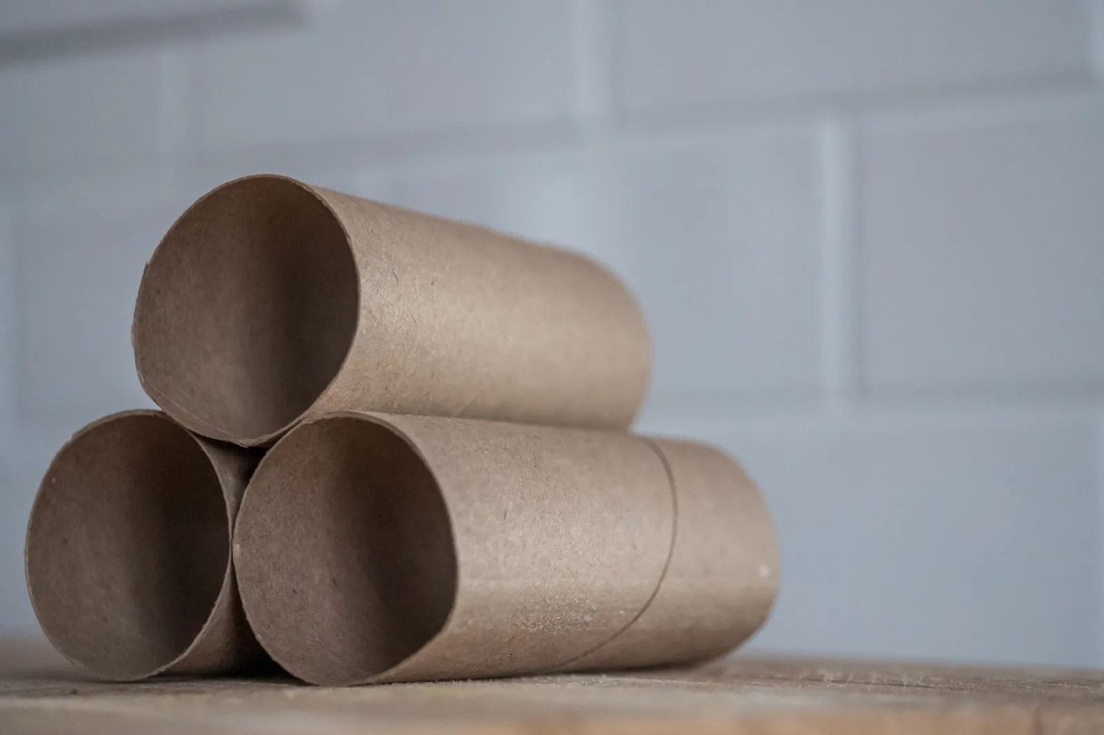 Closeup of stacked brown cardboard tubes of finished toilet paper placed on wooden table