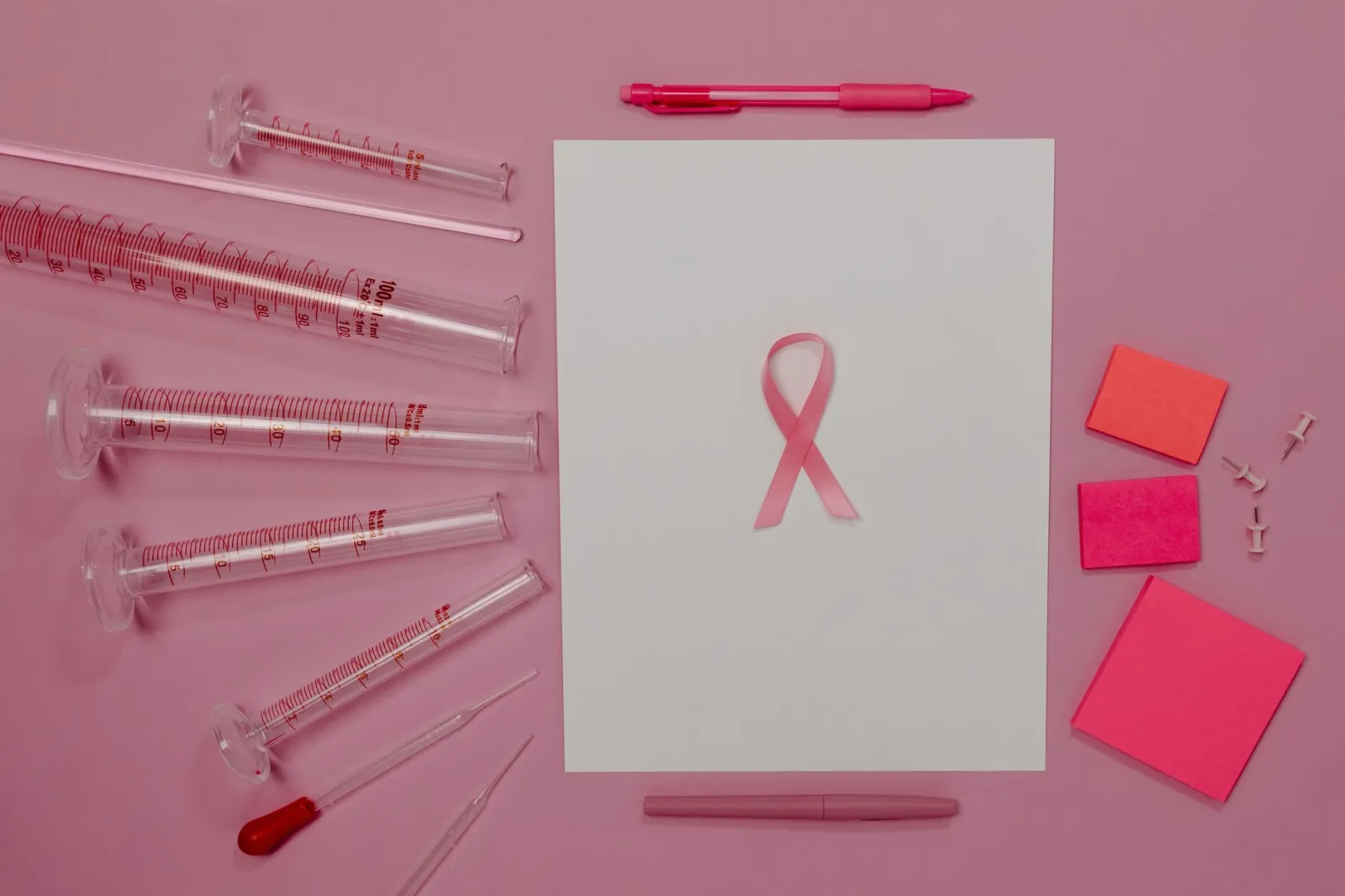 Pink ribbon and lab equipment symbolize breast cancer awareness and research.